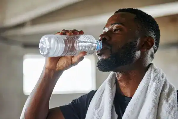 Hydration: The Secret Ingredient for a Toned Stomach and Enhanced Fitness 1 Image of man drinking water to improve hydration Midlands after work out.
